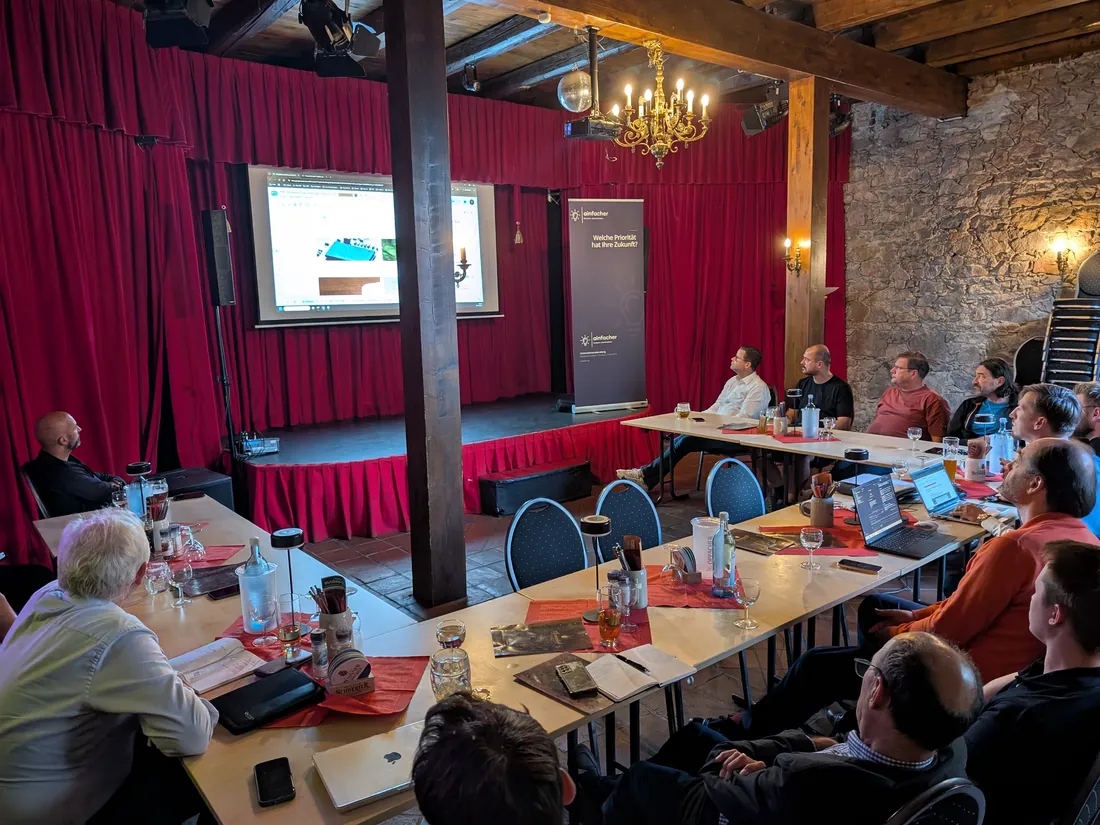 Teilnehmer des 2. KI-Stammtischs verfolgen eine Live-Demo auf der Leinwand