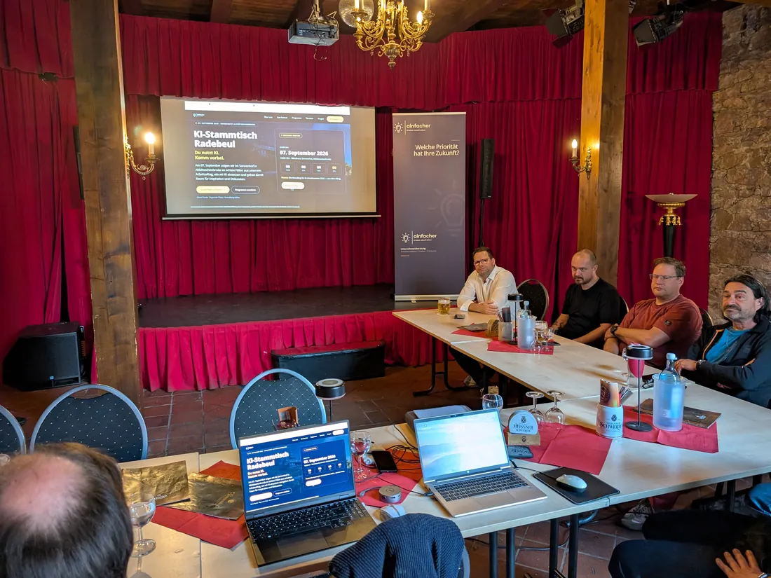 Der 2. KI-Stammtisch Radebeul in der Scheune des Wirtshaus Sonnenhof: Leinwand, Bühne und Teilnehmer an der Tafel